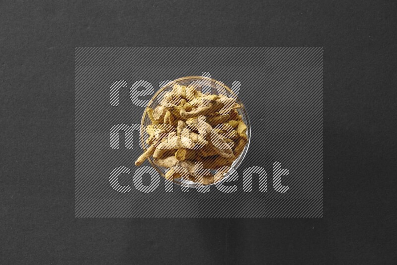 A glass bowl full of turmeric on black flooring