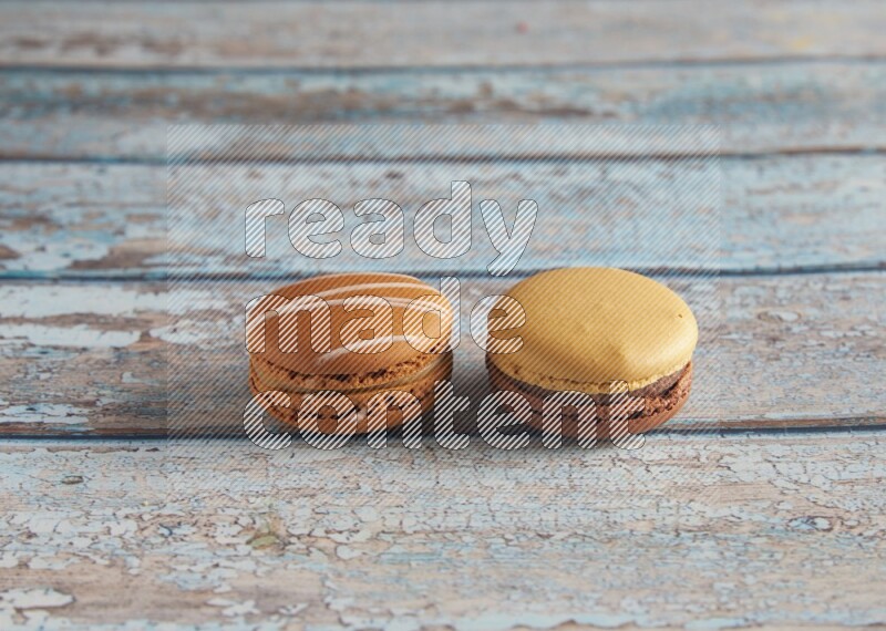 45º Shot of of two assorted Brown Irish Cream, and Yellow, and Brown Chai Latte macarons  on light blue background