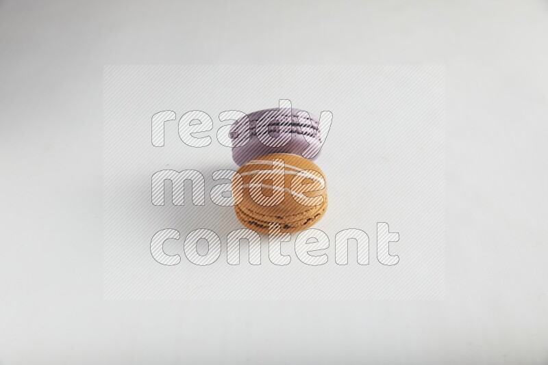 45º Shot of of two assorted Brown Irish Cream, and Purple Blueberry macarons on white background