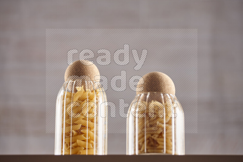 Raw pasta in glass jars on beige background