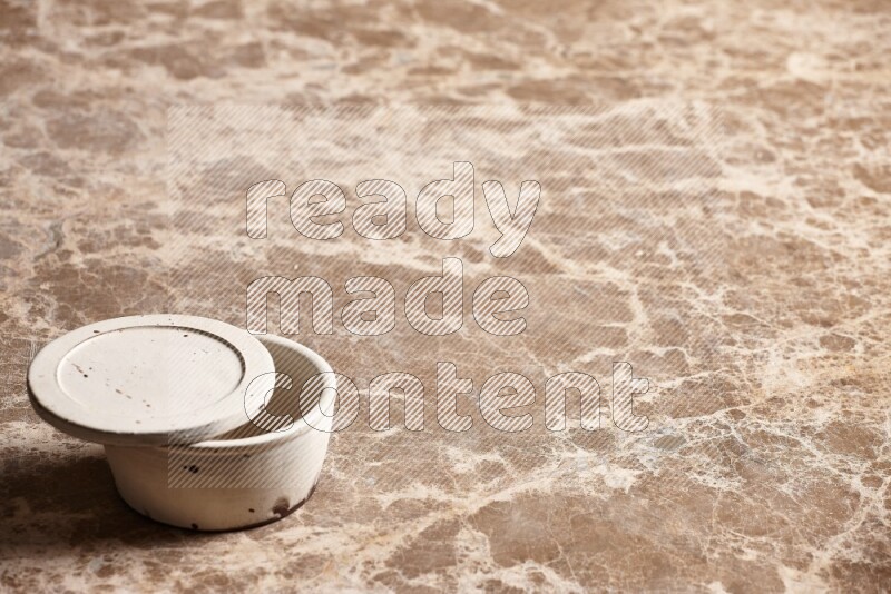 A white pottery bowl on beige marble background