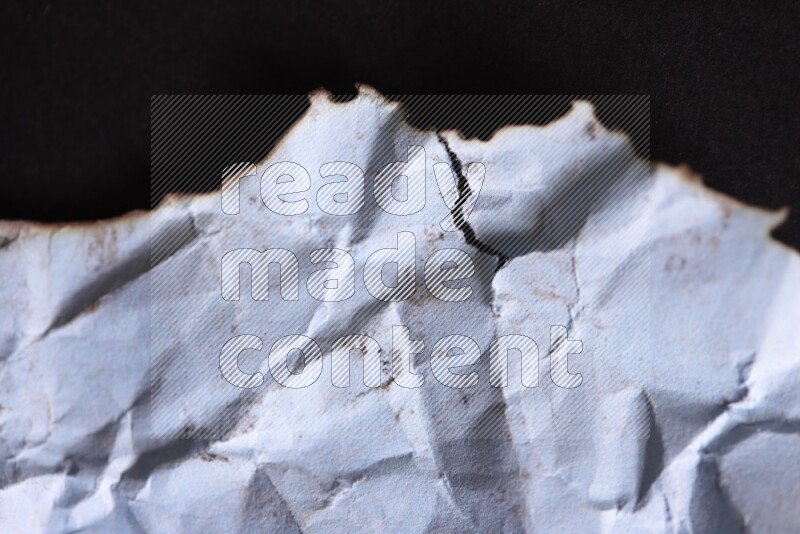 Burnt multicolored paper on black background