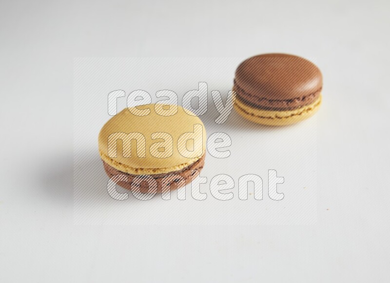 45º Shot of two Yellow and Brown Chai Latte macarons on white background
