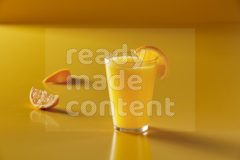 glass of orange juice with orange slice on yellow background