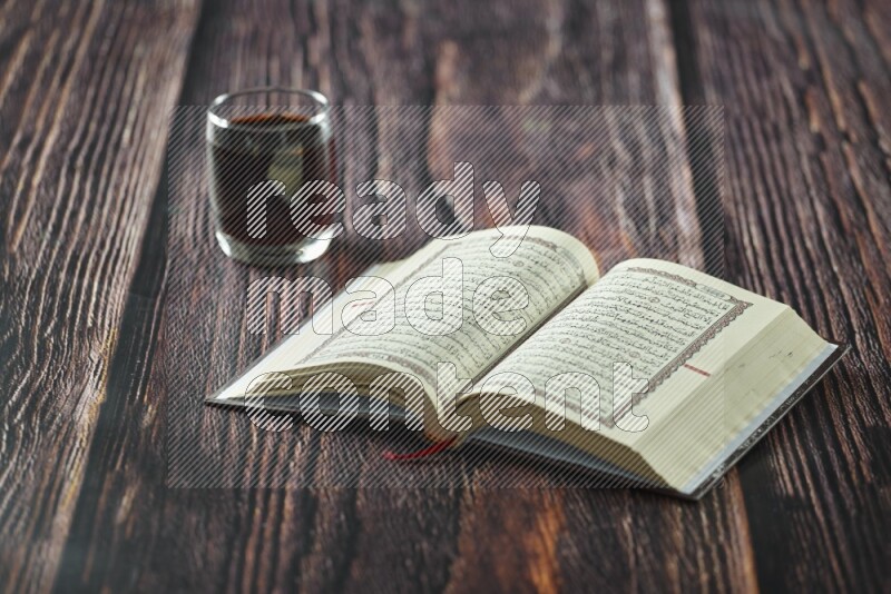 Quran with dates, prayer beads and different drinks all placed on wooden background