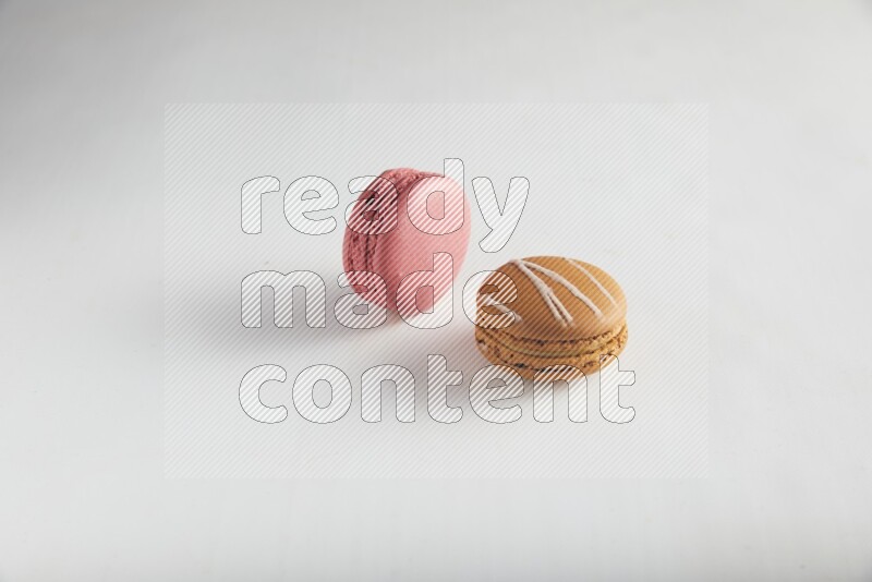 45º Shot of of two assorted Brown Irish Cream, and Pink Raspberry macarons on white background