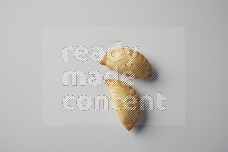 Two fried sambosa from a top angle on a white background