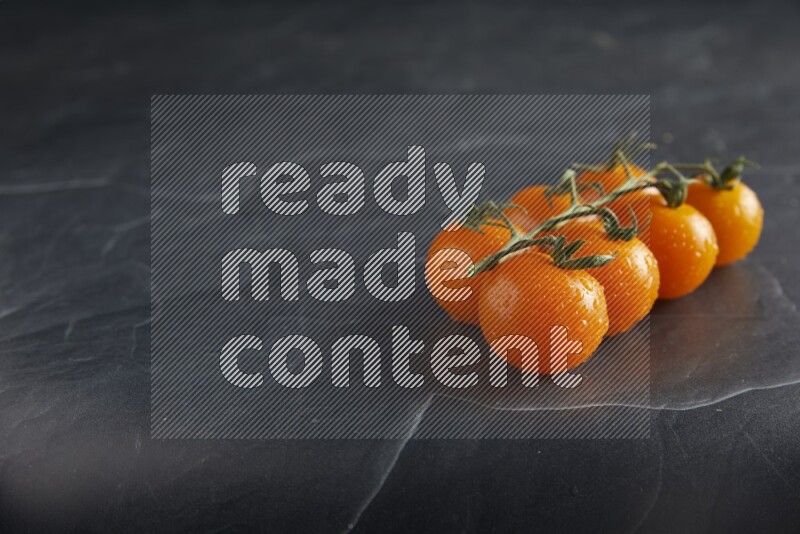 Orange cherry tomato vein on a textured black slate background 45 degree