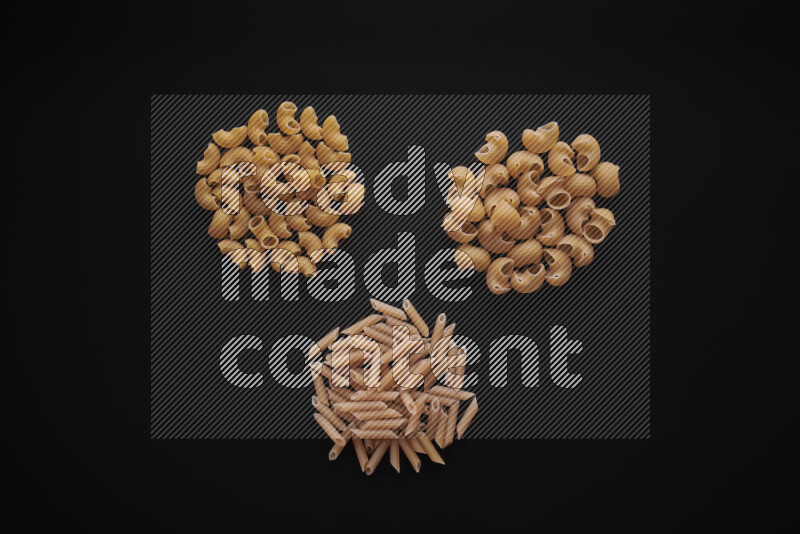 Different pasta types in bunches on black background