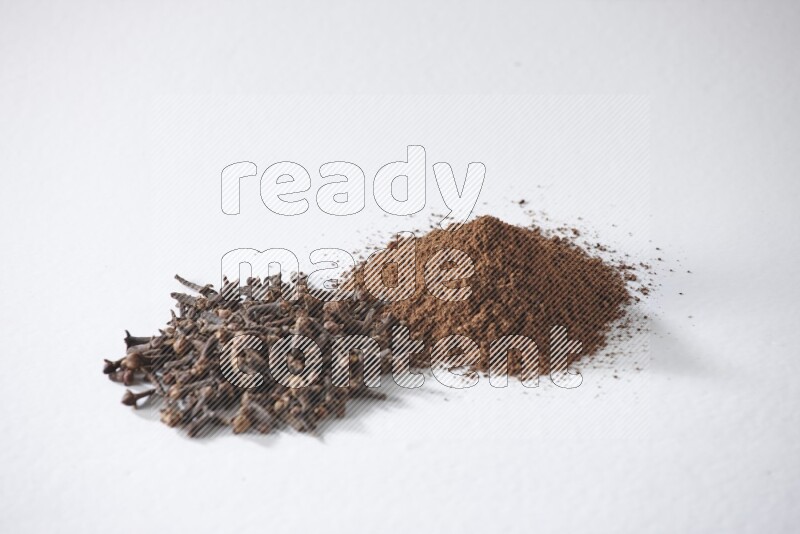 2 piles of cloves grains and cloves powder on a white flooring