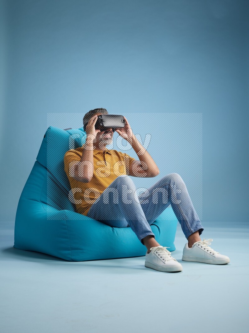 A man sitting on a blue beanbag and gaming with VR