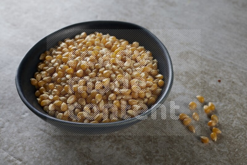 corn kernel in a black ceramic bowl on a grey textured countertop