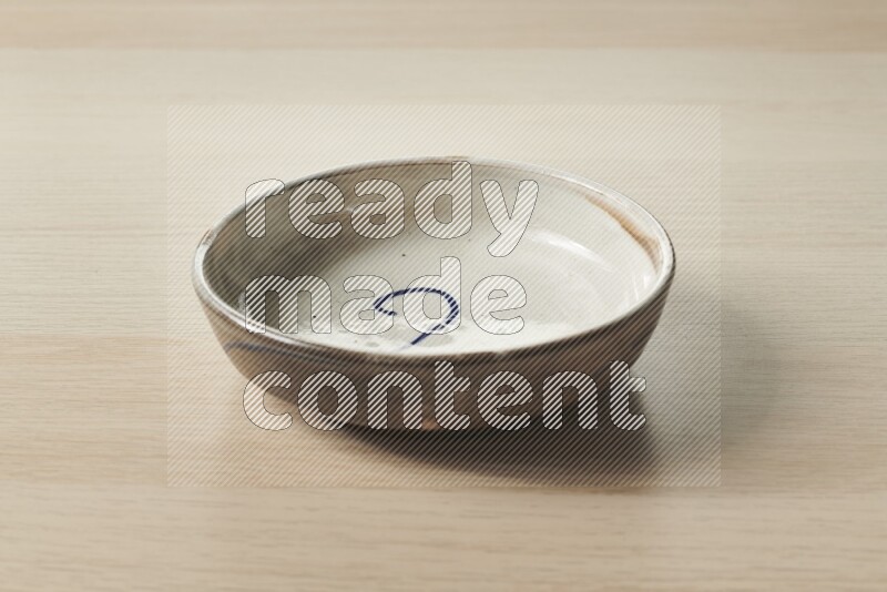 A multicolored pottery bowl on light wooden background