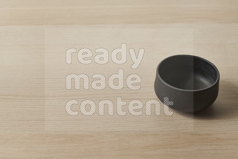 A black pottery bowl on light wooden background