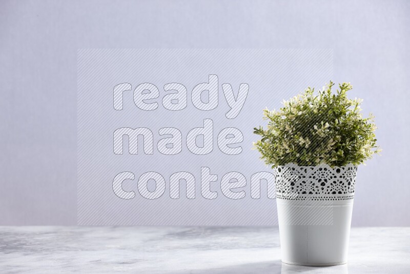 Artificial plant in white decorative pot on grey marble background