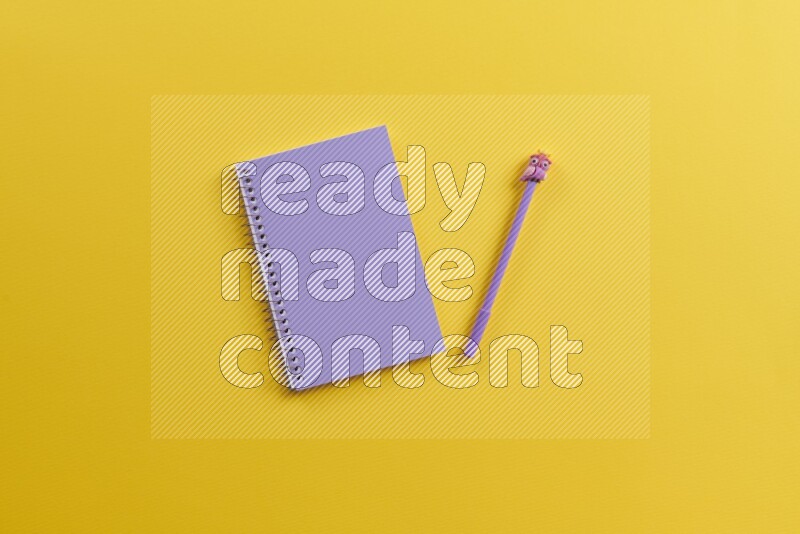 A purple notebook with different school supplies on yellow background