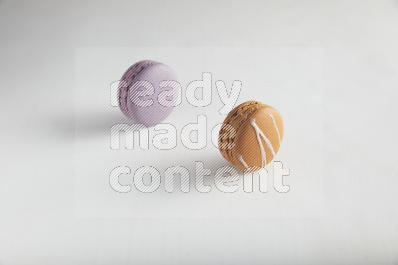 45º Shot of of two assorted Brown Irish Cream, and Purple Blueberry macarons on white background