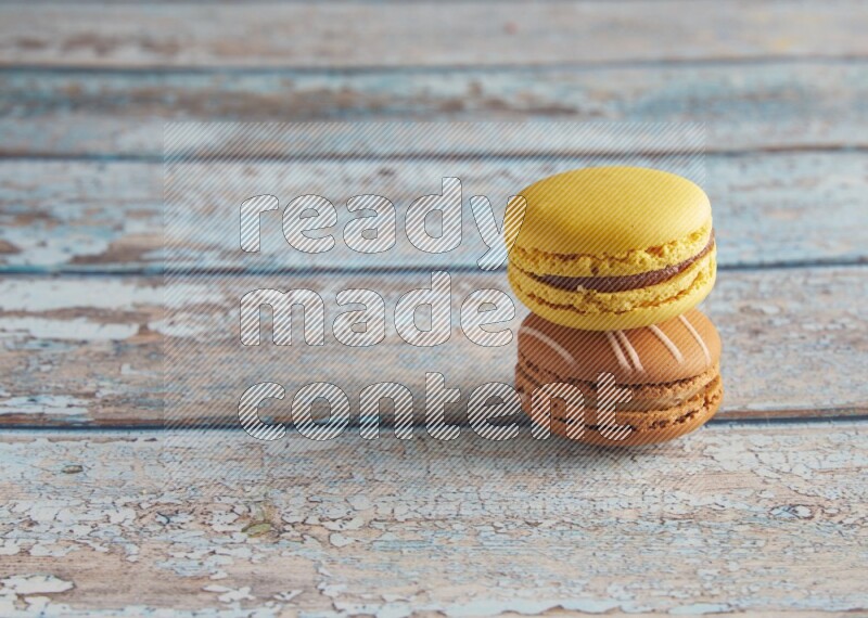 45º Shot of of two assorted Brown Irish Cream, and Yellow Lemon macarons on light blue background
