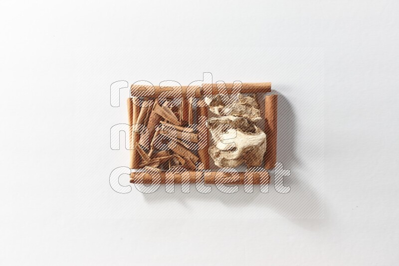 2 squares of cinnamon sticks full of cinnamon and dried ginger on white flooring