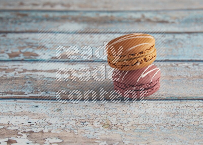 45º Shot of of two assorted Brown Irish Cream, and Red Poppy Flower macarons  on light blue background