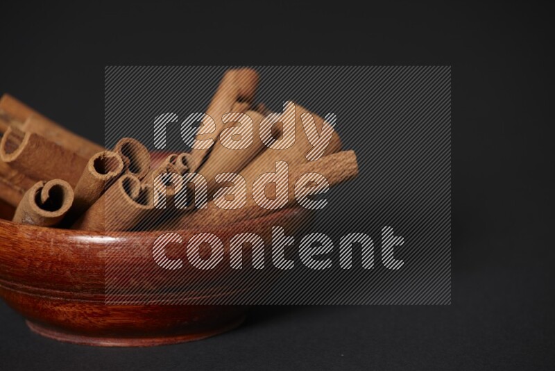 Cinnamon Sticks in a wooden bowl on black background
