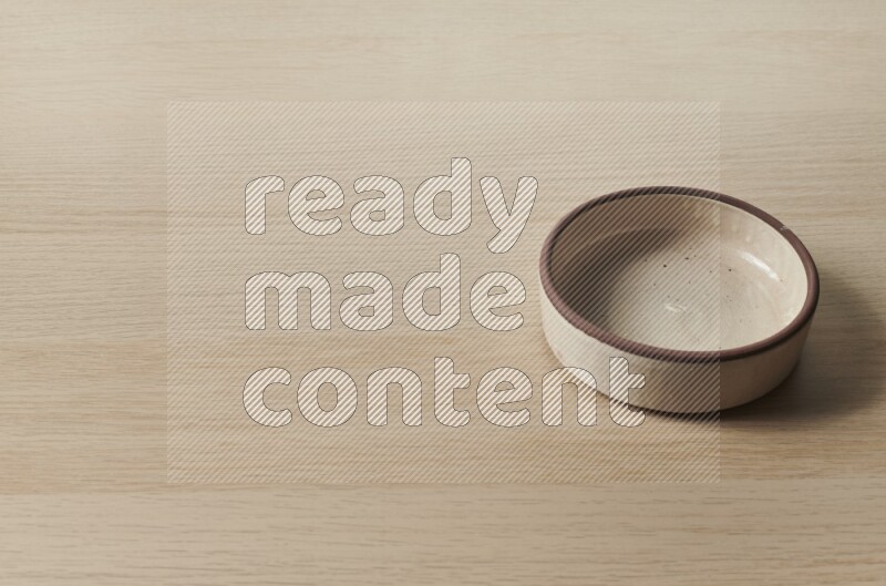 A beige pottery oven bowl on light wooden background