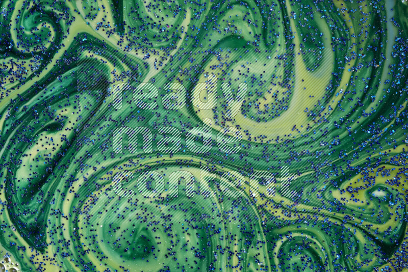 A close-up of sparkling blue glitter scattered on swirling blue and green background