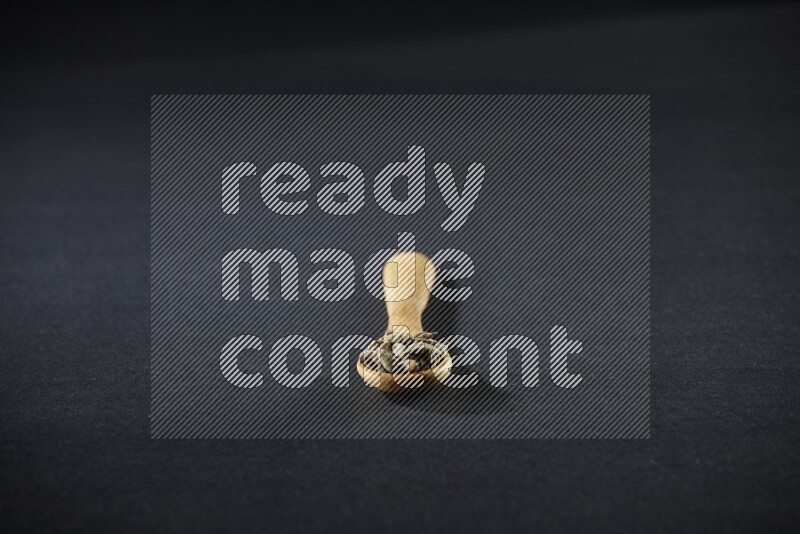 ملعقة خشبية ممتلئة بالهيل على خلفية سوداء