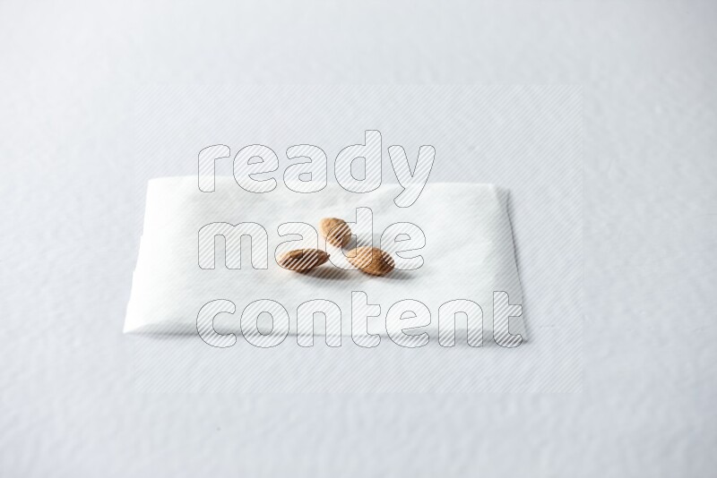 3 peeled almonds on a piece of paper on a white background in different angles