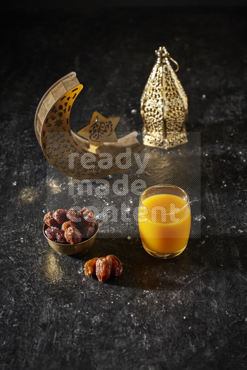 Dates in a metal bowl with qamar el din beside golden lanterns in a dark setup