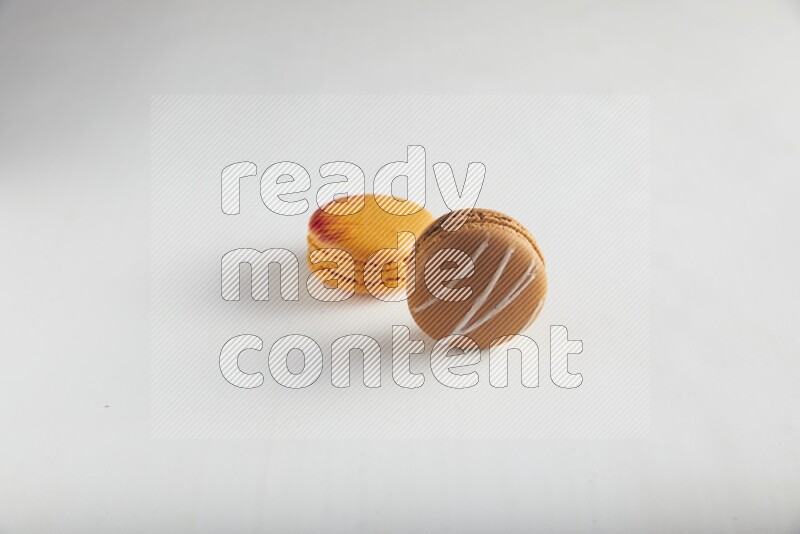 45º Shot of of two assorted Brown Irish Cream, and Orange Exotic macarons on white background