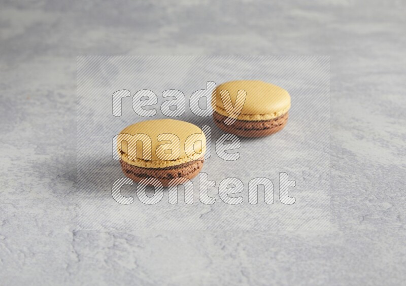 45º Shot of two Yellow and Brown Chai Latte macarons r on white  marble background