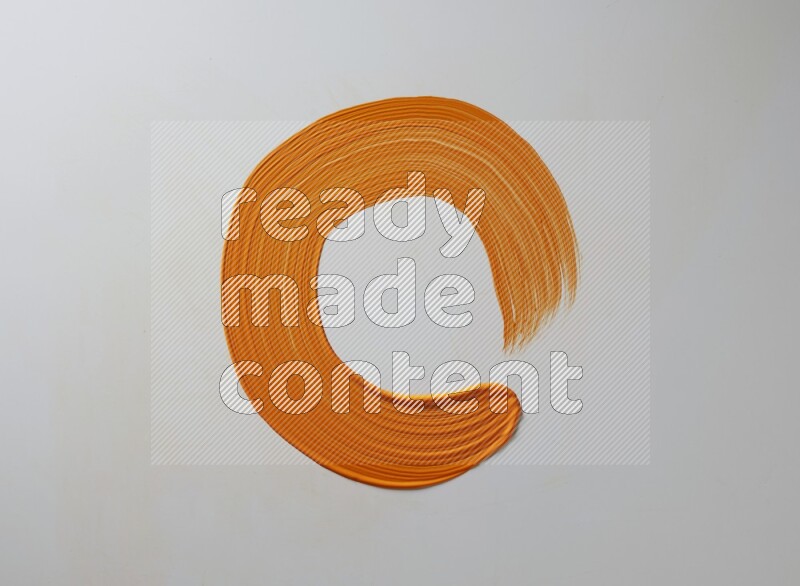 An orange circular painting brush stroke on white background