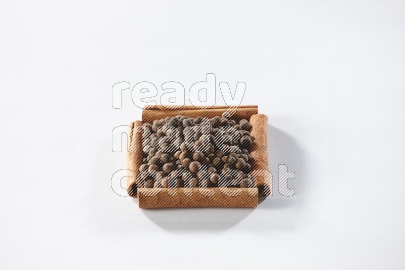 A single square of cinnamon sticks full of allspice on white flooring