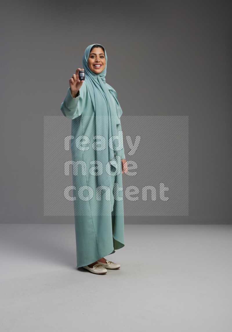 Saudi Woman wearing Abaya standing holding car key on Gray background