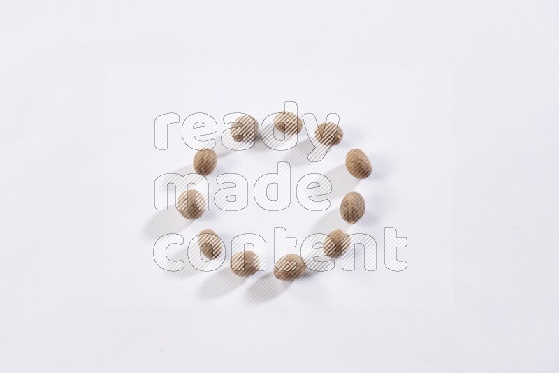 Nutmeg seeds in a circle shape on a white flooring