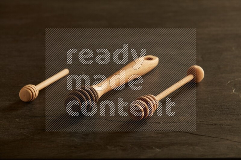 Wooden honey dipper on black slate background