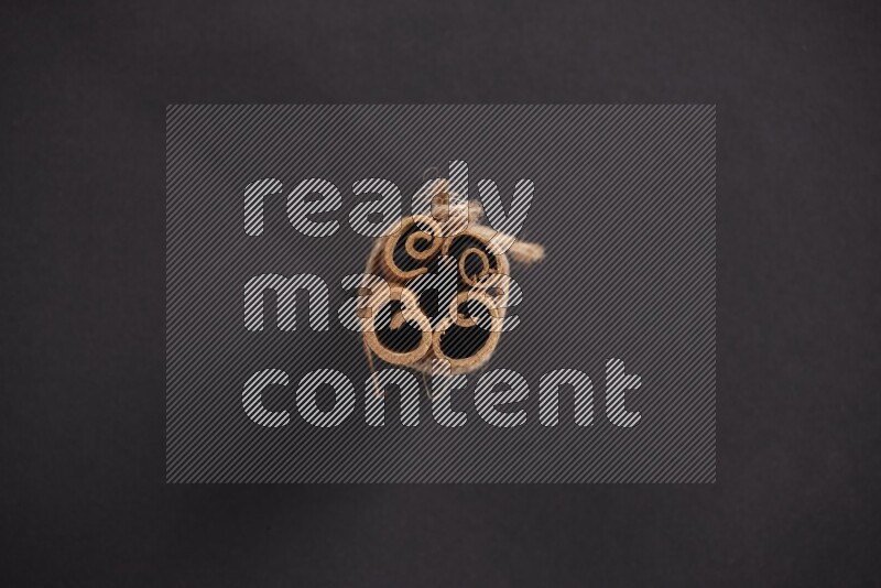 4 Cinnamon sticks stacked and bounded on black flooring