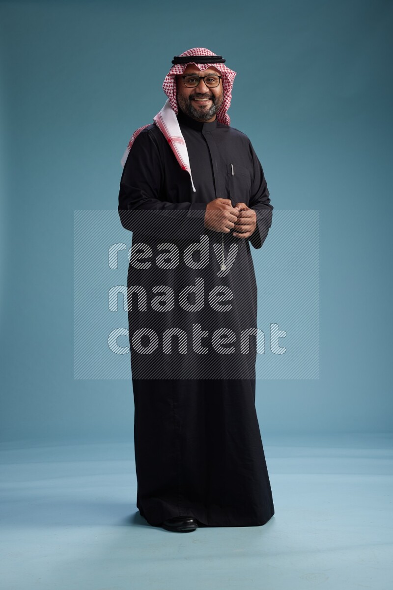 Saudi Man with shimag Standing Interacting with the camera on blue background