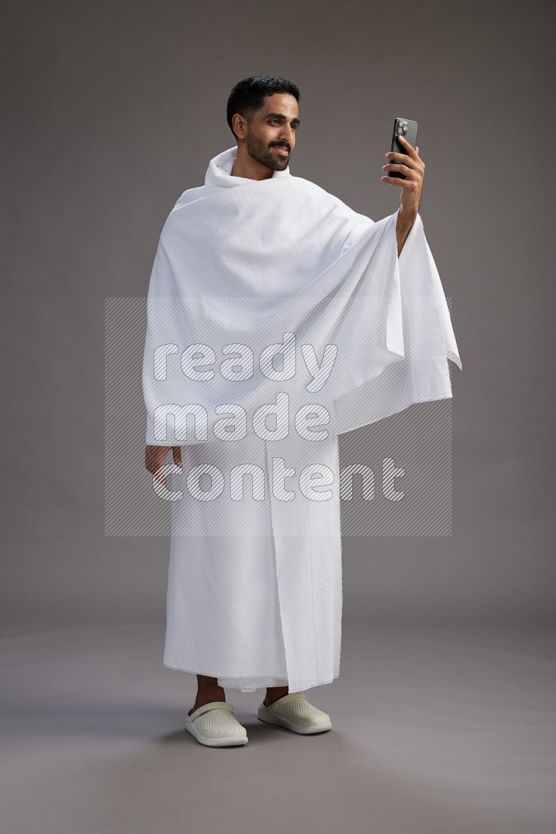A man wearing Ehram Standing taking selfie on gray background