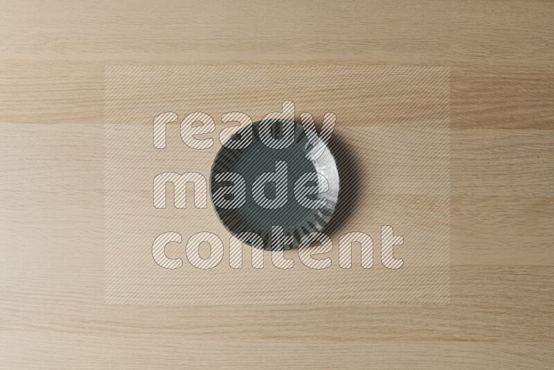 A dark green pottery plate on light wooden background