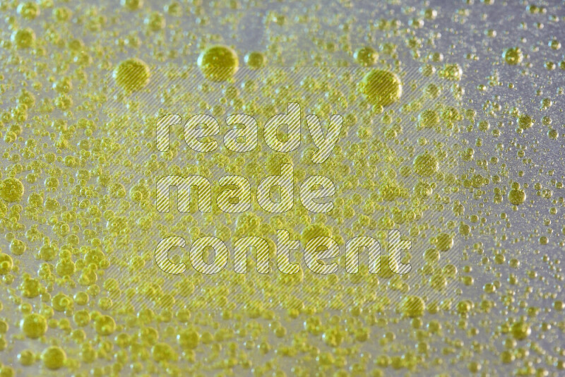 لقطات مقربة لقطرات ألوان مائية صفراء على سطح الزيت على خلفية بيضاء