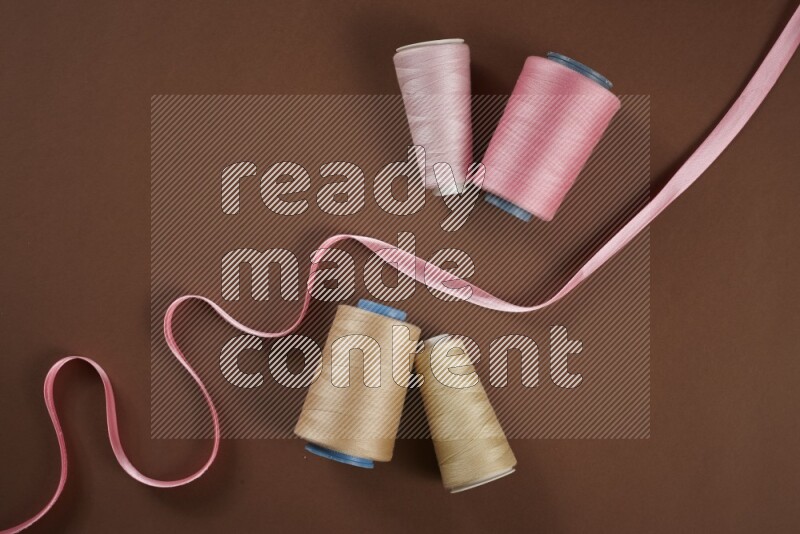 A pink collection of sewing and tailoring tools arranged on a brown background