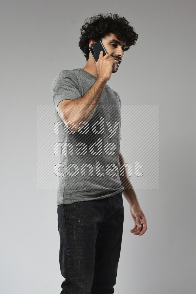 A man wearing casual standing and talking on the phone on white background
