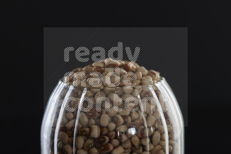 Black-eyed peas in a glass jar on black background