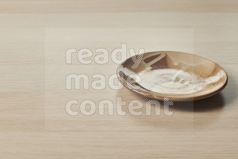 A multicolored pottery plate on light wooden background