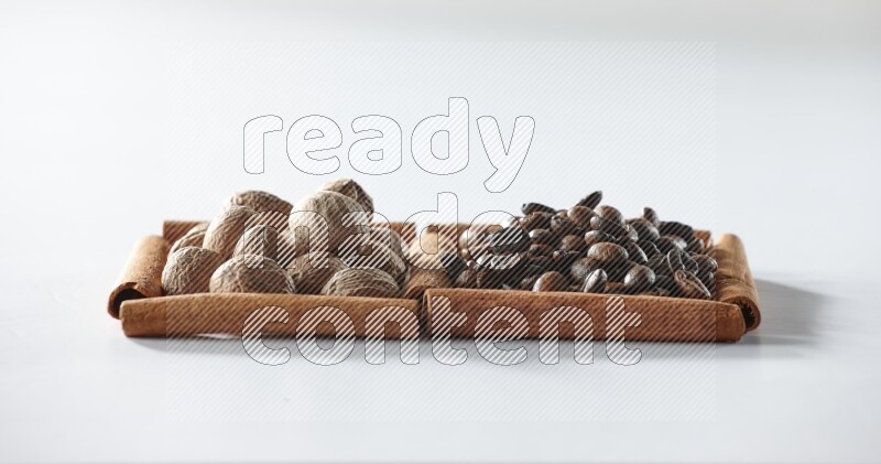 2 squares of cinnamon sticks full of coffee beans and nutmegs on white flooring