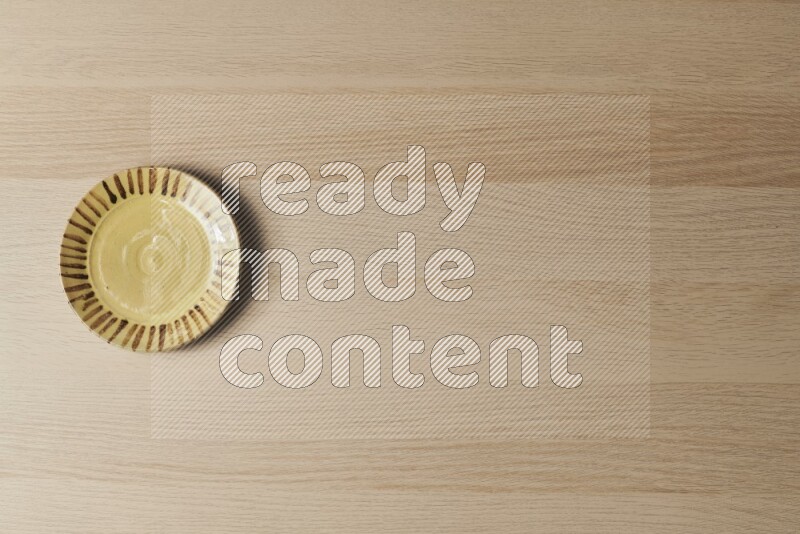 A multicolored pottery plate on light wooden background