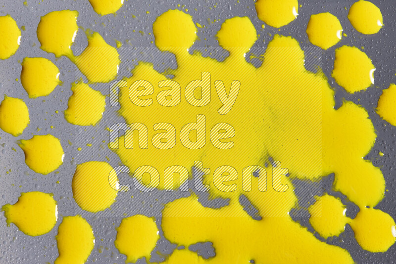 Close-ups of abstract yellow paint droplets on grey background
