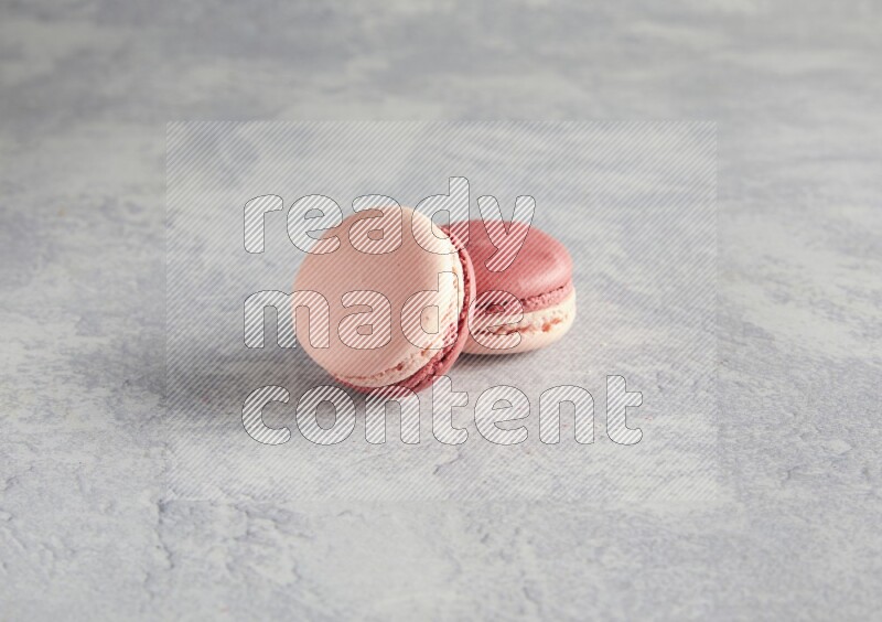 45º Shot of two Pink Litchi Raspberry macarons  on white  marble background